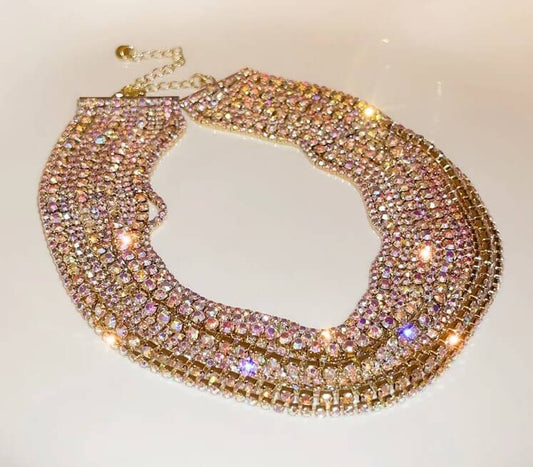 Gold necklace with multicolored gemstones on a light background