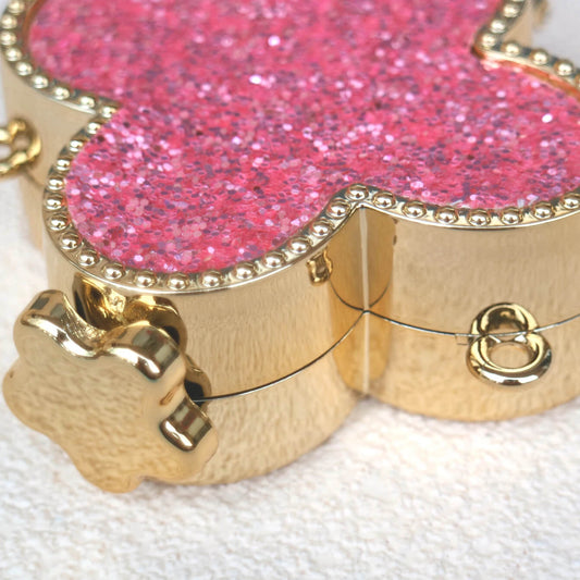 Pink glittery heart-shaped box with gold accents on a white background