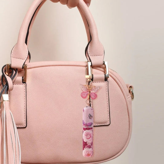 Pink handbag with a decorative charm on a beige background