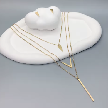Gold necklace with a white ceramic dish on a gray background