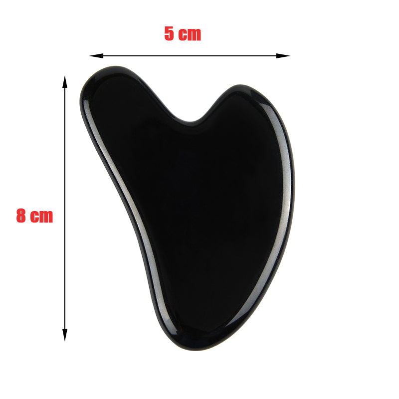 A collection of natural stone Gua Sha massagers in various colors including black, blue, green, pink, and purple, alongside a raw piece of pink stone. The massagers are designed in a heart shape with a smooth, curved surface.