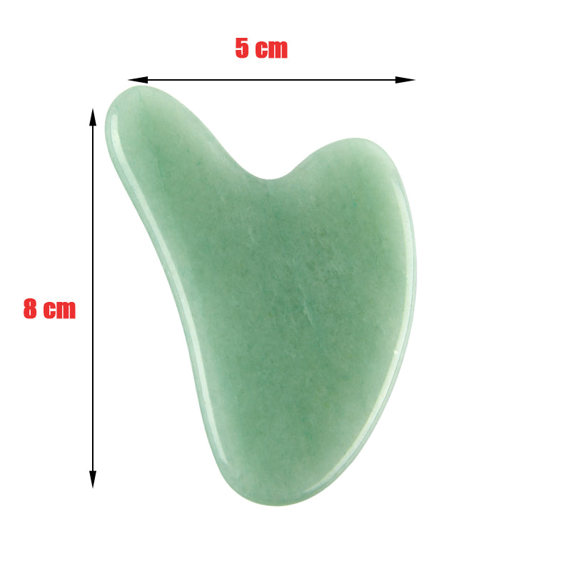 A collection of natural stone Gua Sha massagers in various colors including black, blue, green, pink, and purple, alongside a raw piece of pink stone. The massagers are designed in a heart shape with a smooth, curved surface.
