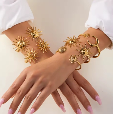 Gold sun and moon bracelet on a hand against a neutral background