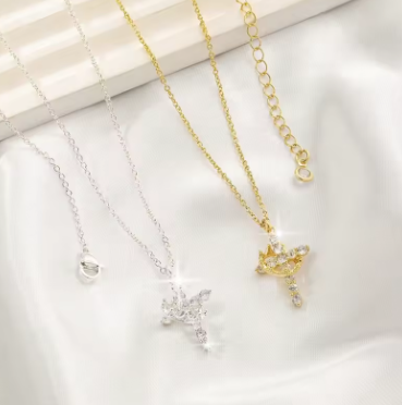 Two necklaces, one gold and one silver, on a light wooden surface.