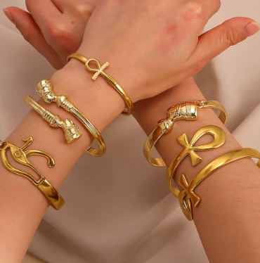 Gold bracelets with various designs on a neutral background