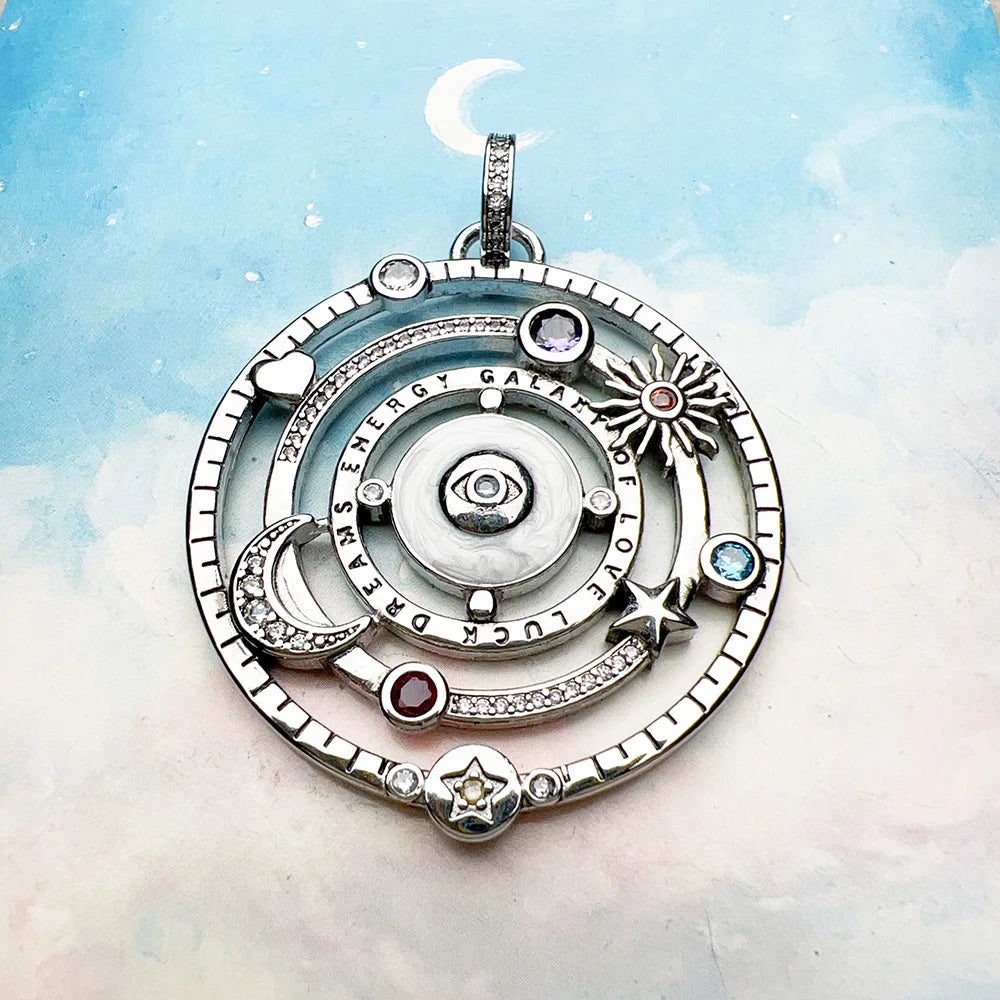 Silver pendant with celestial design on a soft blue and white background