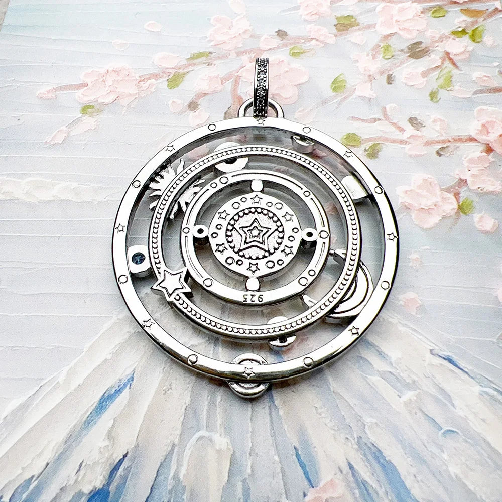Silver circular pendant with star design on a light background with floral elements