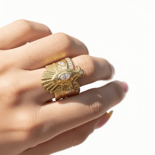 Gold ring with feather design on a hand against a white background