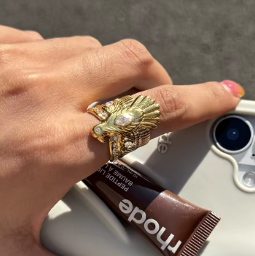 Hand wearing a gold eagle ring with a blurred background