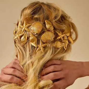 Blonde hair with decorative gold shells and starfish on a beige background