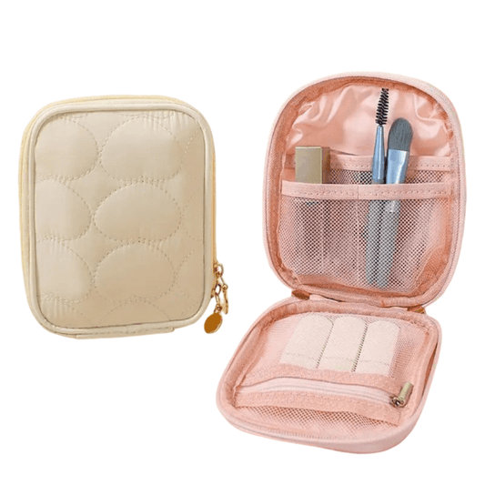 Pink makeup case with quilted design and gold zipper, containing brushes and other items.