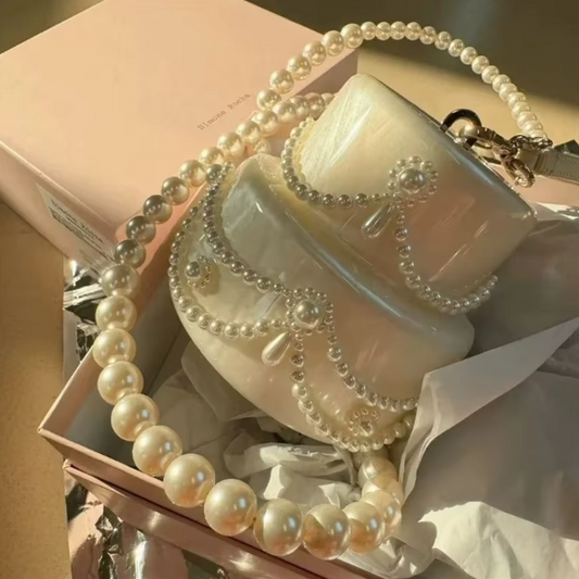 White mug with pearl necklace on a pink surface