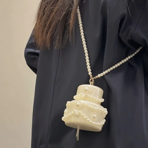 Pearl necklace with a decorative pendant worn by a person against a neutral background