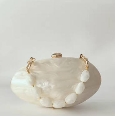 White shell clutch with gold accents on a light gray background