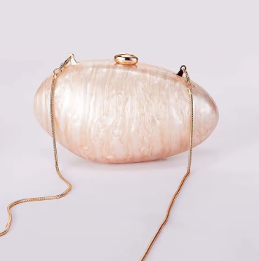 Pink handbag with gold chain strap on a light gray background