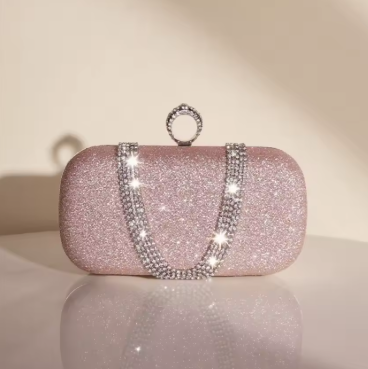 Sparkling pink clutch bag with rhinestone chain on a reflective surface