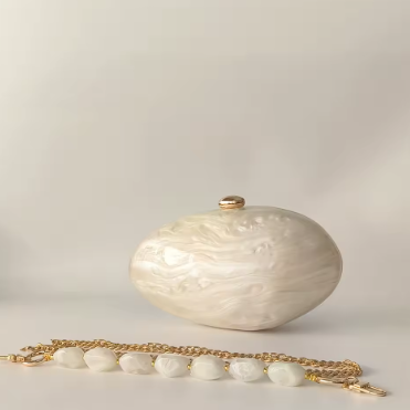 White textured clutch with gold chain on a light gray background